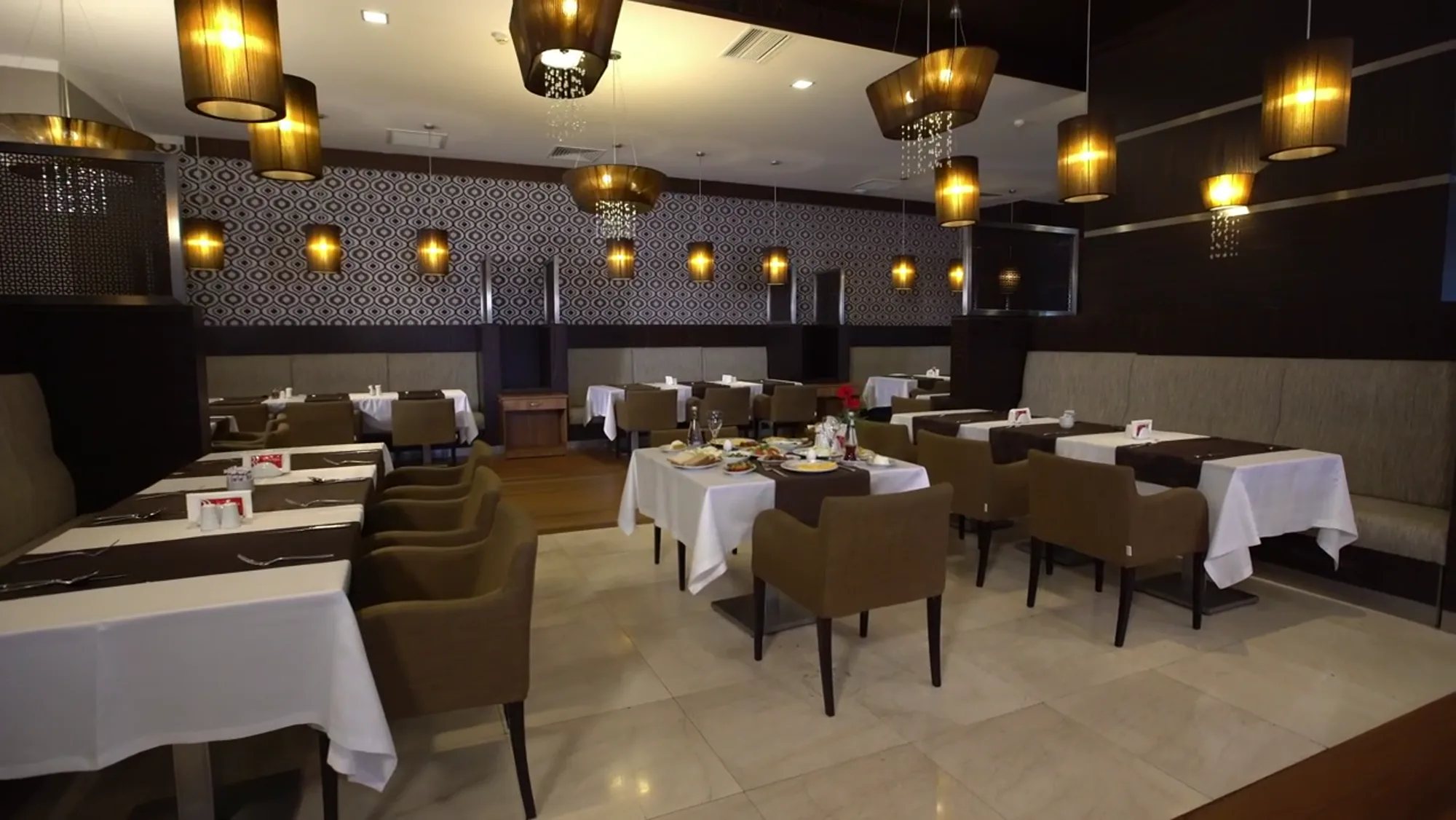 The dining room with warm pendant lights and white tablecloths