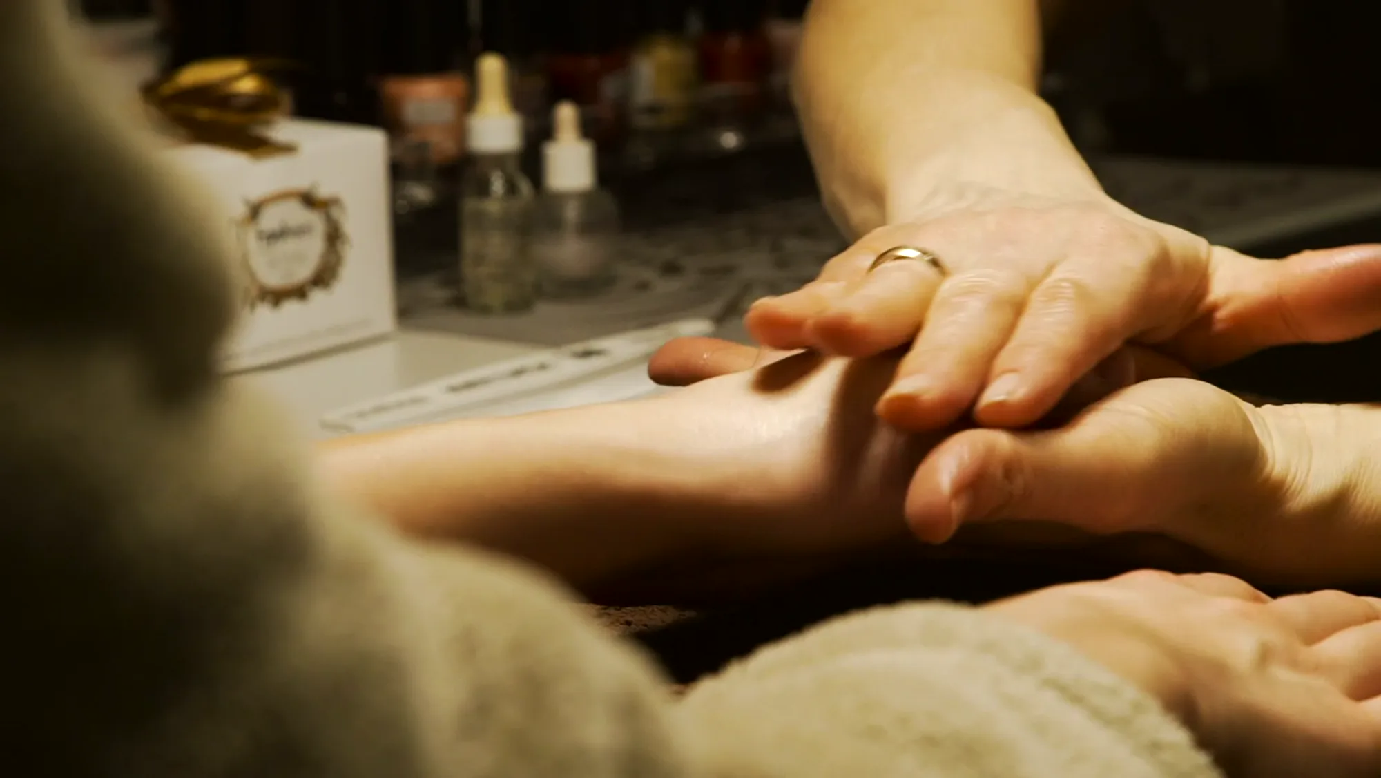 A therapist massaging a guest’s hands with warm oil